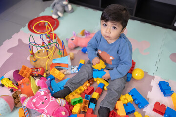 Wall Mural - two years old mexican baby boy playing with didactic toy on messy living room