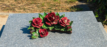 Red Ceramic Rose Flowers On Tomb In Cemetery. France. Traditional Ceramic Grave Decoration. Mourning Background. Loss, Grief, Sorrow, Memorial  Concepts. Selective Focus. 
