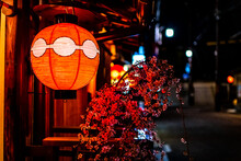 Kyoto, Japan Colorful Street Road Alley In Gion District At Night Evening With Closeup Of Illuminated Traditional Red Paper Lantern Lamp And Cherry Blossom Sakura Flowers Decorations
