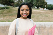 © Xavier Lorenzo - Portrait of smiling young hispanic latina student girl holding file while standing at campus school university