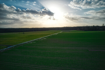 Poster - A scenic view of a road surrounded by green meadows on cloudy sky background