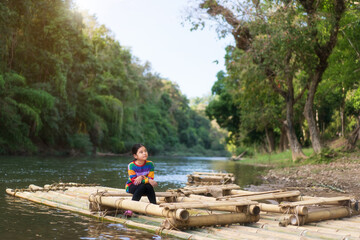 asian child or kid girl and person tourism sitting alone on wooden nature bamboo raft float on water river to holiday travel relax on summer vacation at mae ngao national park mae hong son in thailand