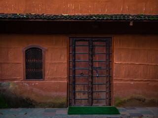 Wooden door and artistic window with red colored wall.