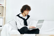 © SHOTPRIME STUDIO - curly guy on a white sofa in front of a laptop learning Lifestyle technology