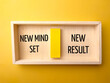 Top view wooden box with text New mind set and new result on a yellow background.