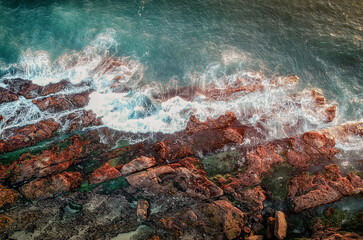 Poster - Beautiful view of wavy foam on rough rocks on the beach