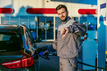 A Gas Station Worker Filling Up The Car Tank With Diesel And Giving Thumbs Down For Price Increase Of Diesel.