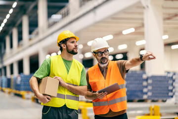 Wall Mural - A boss with tablet showing to warehouse worker with box where to put it.