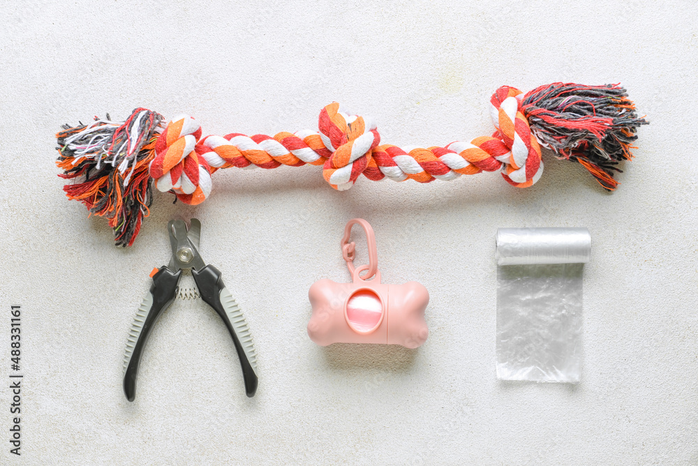 Pet waste bags, nail clipper and toy on light background