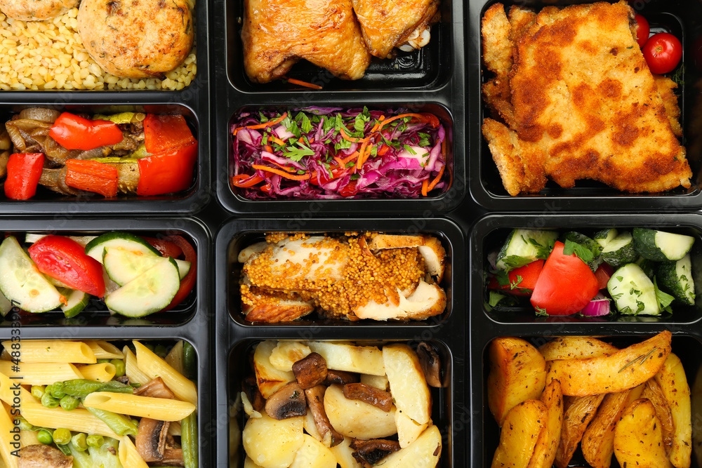 Different delicious food in lunch boxes as background