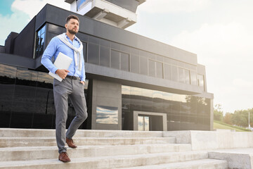 Wall Mural - Handsome businessman with laptop going downstairs