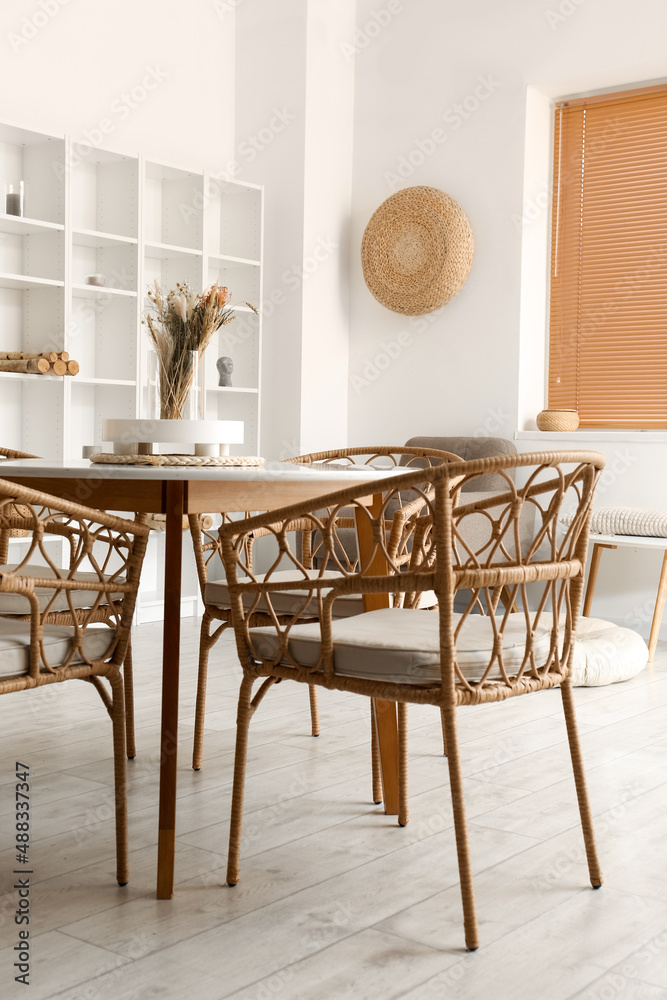 Interior of light dining room with table and shelving unit