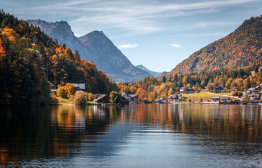 Fotobehang - Scenic panorama of beautiful alpine autumn view with lake, mountains, green meadow and perfect sky. Amazing nature scenery. Wonderful sunny landscape. Grundlsee. Austria