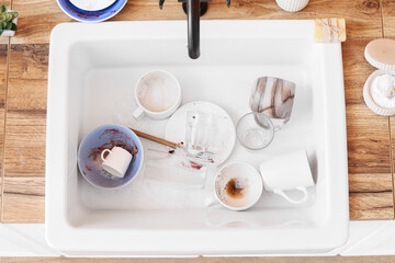 Dirty dishes in white ceramic sink, top view