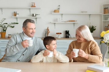 Wall Mural - Little boy and his grandparents in warm sweaters with cups of cocoa at home