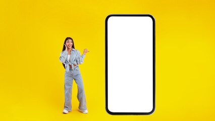 Woman showing white empty smartphone screen and pointing at panel