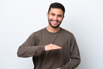 Sticker - Young Brazilian man isolated on white background holding copyspace imaginary on the palm to insert an ad