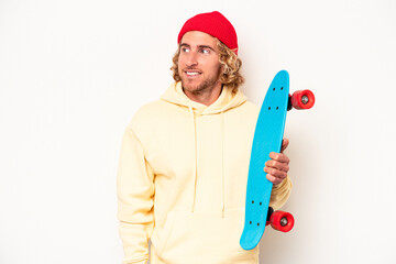 Wall Mural - Young skater caucasian man isolated on white background looks aside smiling, cheerful and pleasant.