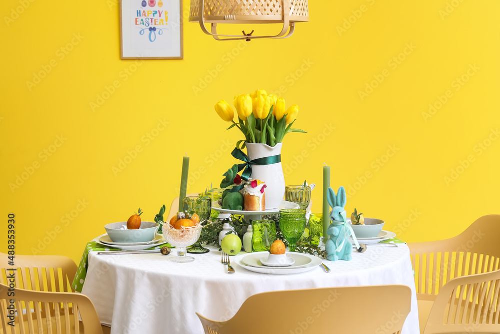 Stylish dinnerware on table served for Easter celebration near color wall