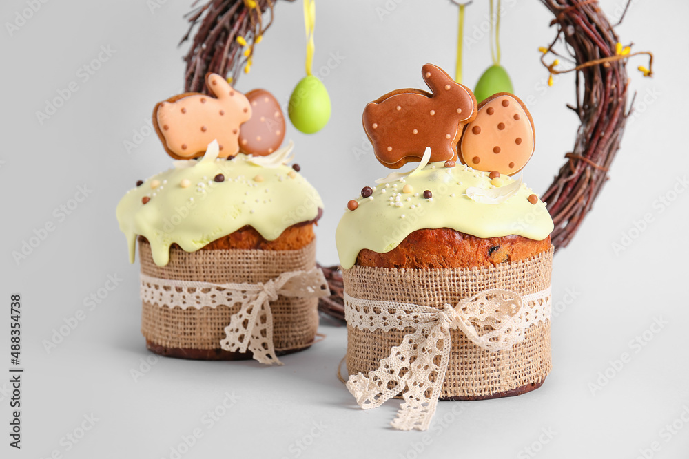 Delicious Easter cakes decorated with cookies on light background