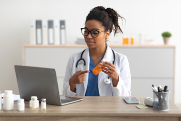 Portrait of black female medical practitioner using laptop