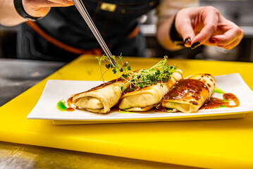 Wall Mural - chef cooking food. Chef's hands cooking pancakes crepe rolls with ground meat on kitchen