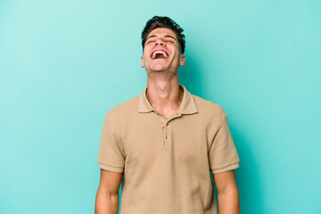 Young caucasian man isolated on blue background relaxed and happy laughing, neck stretched showing teeth.