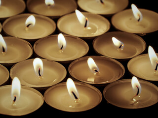 Tealight candles burning on a black background. Concept of death, loss, and mourning