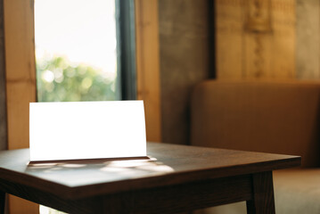 Menu with isolated white on wooden table on blurred restaurant background