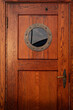 Old ship wooden door with porthole. Vintage sailing boat crew cabin entrance with round window. Beautiful sea and yacht concept backdrop. Vertical, close up, copy space