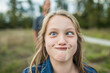 © Cavan Images - Young girl makes sill face, crazy eyes, grass in mouth.