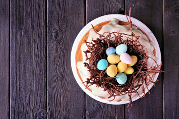 Poster - Easter bundt cake with chocolate nest of colorful candy eggs. Top view over a dark wood background.