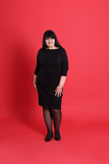 Wall Mural - Beautiful overweight woman in black dress on red background