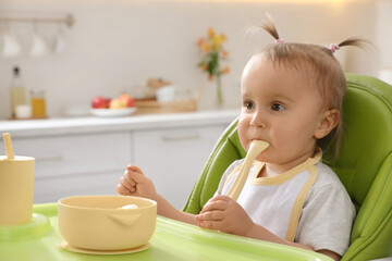 Canvas Print - Cute little baby eating food in high chair at kitchen