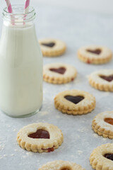 Wall Mural - Heart shaped Valentines day or holiday homemade cookies with different jams  and jar of milk in the background from a vertical elevated front angle on a marble table.