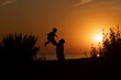 © IrinaStrelnikova - Silhouette of a man and a child against the sunset.Dad raises his son