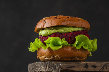 Vegan burger with beetroot, avocado sauce and lettuce salad on black background. Healthy vegetarian food