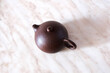 © Olga Panova - Brown clay teapot for brewing tea close-up on a marble countertop, top view, three-quarter turn
