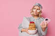 © WHstudio Leushin N - Unhappy annoyed woman looks angrily away makes plannings in mind uses mobile phone for surfing internet holds bowl of pancakes with raspberries applies beauty patches holds pillow stands indoor