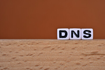 Poster - Word cubes lined up with the letters DNS written on it. It is an abbreviation for Domain Name System. Copy space available.