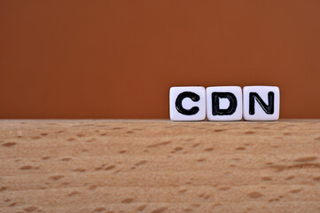 Poster - Word cubes lined up with the letters CDN written on it. It is an abbreviation for Content Delivery Network. Copy space available.