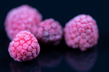 Wall Mural - Close-up of frozen raspberries on black reflecting underground