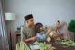 © Odua Images - kid with her parent making a ketupat at home