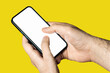 © DIGITALSHAPE - Hand holding a phone with empty white screen on yellow background