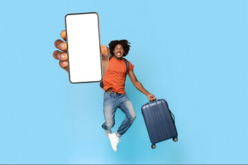 Happy black man with suitcase showing smartphone with empty screen