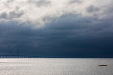 Cloudy Sky Over Sound Strait With Silhouette Of Oresund Bridge In Background
