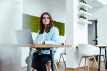 Beautiful Young Businesswoman With Laptop Sitting At Desk In Office