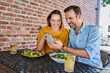 Happy couple sharing smartphone while out in the city eating lunch at outdoors cafe