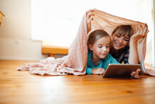 Mother And Son Below Shawl Watching Tablet PC At Home