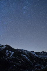 Wall Mural - A vertical shot of a slope of a snowy mountain under the starry night sky